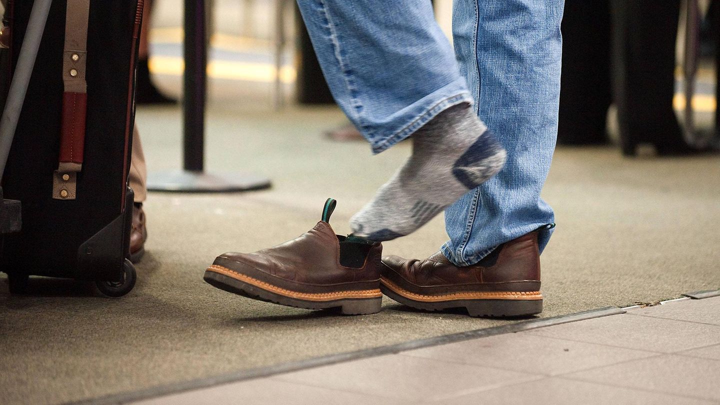 Ein Mann zieht sich bei der Sicherheitskontrolle am Flughafen in den USA die Schuhe aus