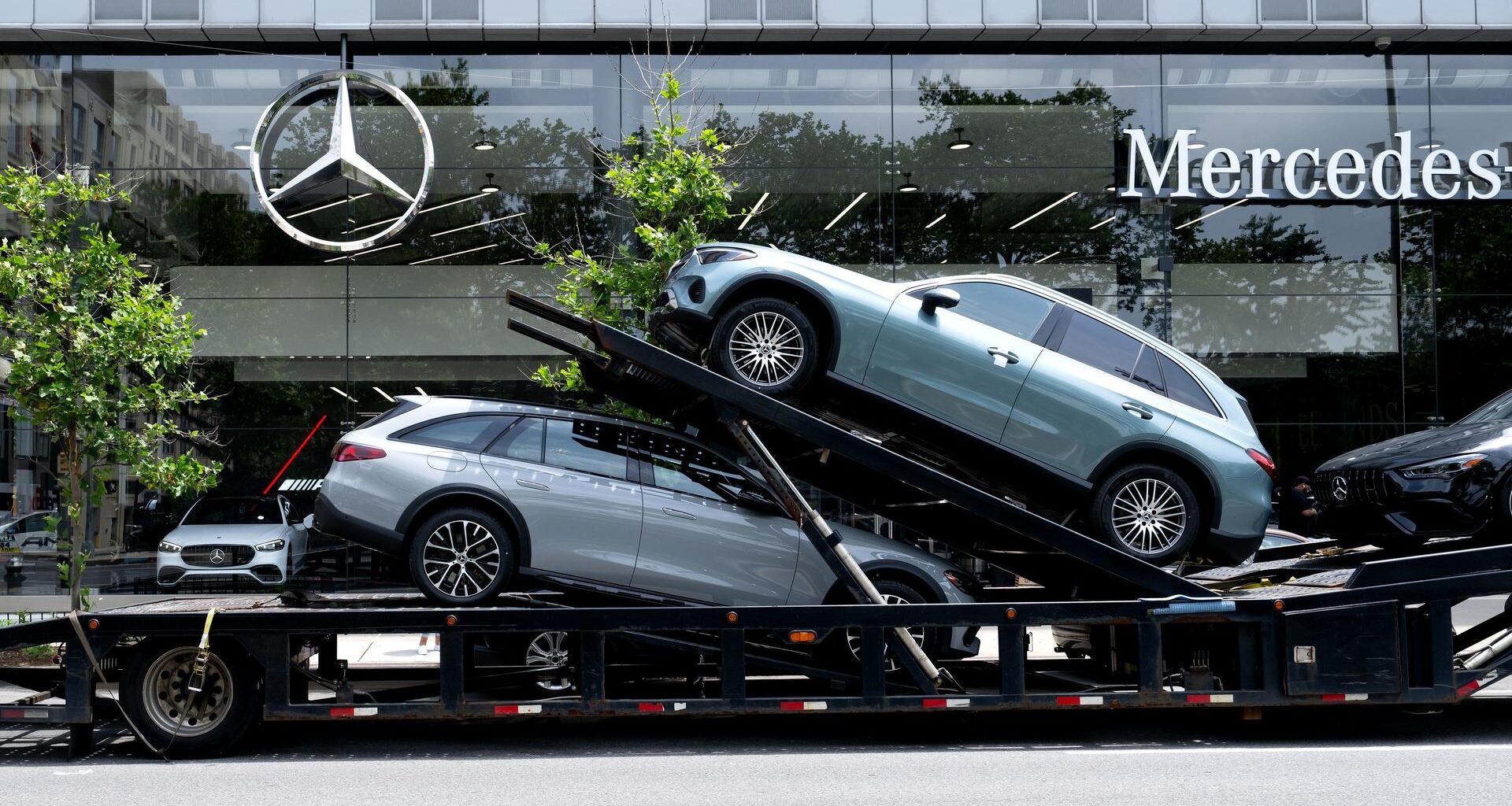 Ein Autotransporter mit Neuwagen von Mercedes-Benz vor einem Autohaus in New York