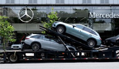 Ein Autotransporter mit Neuwagen von Mercedes-Benz vor einem Autohaus in New York