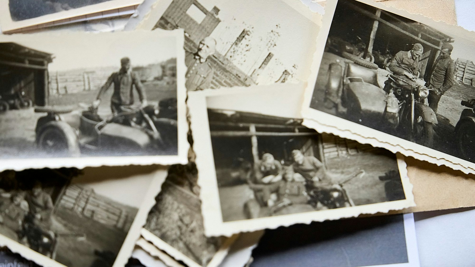 Mehrere alte Schwarz-Weiß-Fotos, die eine SS-Formation aus der Zeit des Nationalsozialismus zeigen, liegen auf einem Haufen.