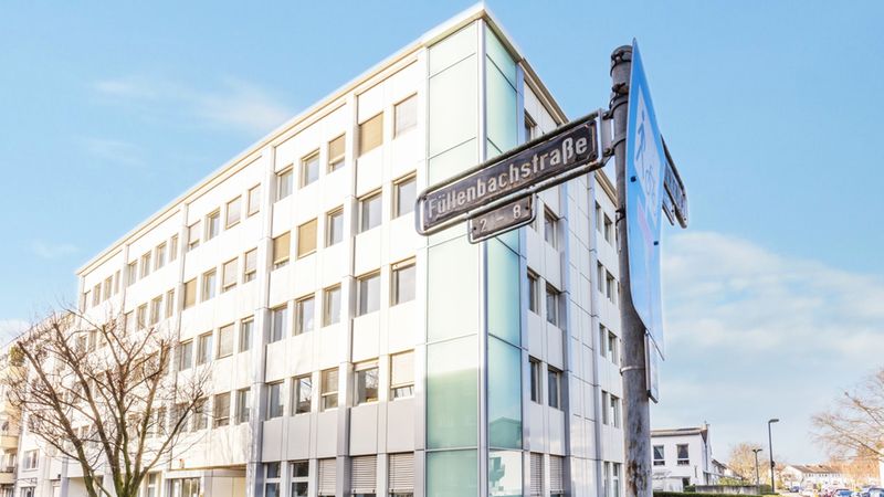Ein modernes Bürogebäude an der Füllenbachstraße mit einem Straßenschild im Vordergrund.