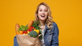 Kundin mit Einkaufstüte im Arm lacht. Symbolbild für typische Sprüche im Supermarkt an der Kasse.