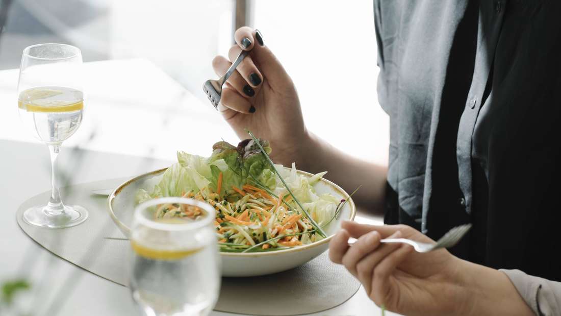 Eine Frau isst einen Salat im Restaurant. 