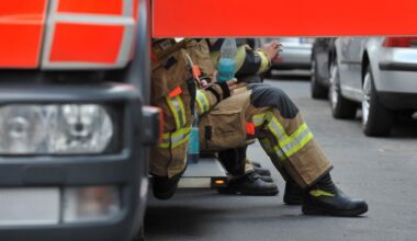 Feuerwehrleute sitzen nach einem Einsatz an einem Einsatzfahrzeug. (Quelle: dpa/Paul Zinken)