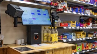 Digitale Kasse und Regale voller Produkte in einem modernen SB-Supermarkt.