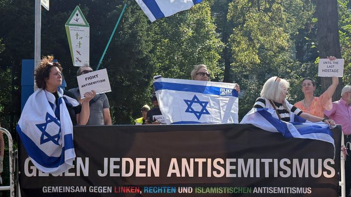 Demonstranten halten israelische Flaggen und protestieren gegen eine umstrittene propalästinensische Solidaritätsveranstaltung der Neuköllner Linke (Quelle: dpa/Paul Zinken).