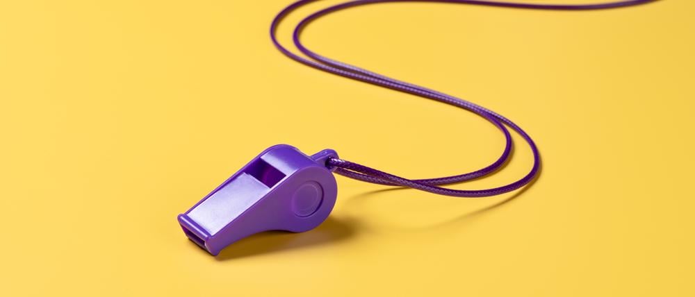 Purple Colored Plastic Whistle With Curved Lanyard on Yellow Background High Angle View.