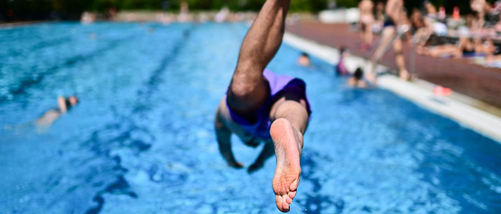 Ein Mann springt im Sommerbad Kreuzberg ins Becken. 
