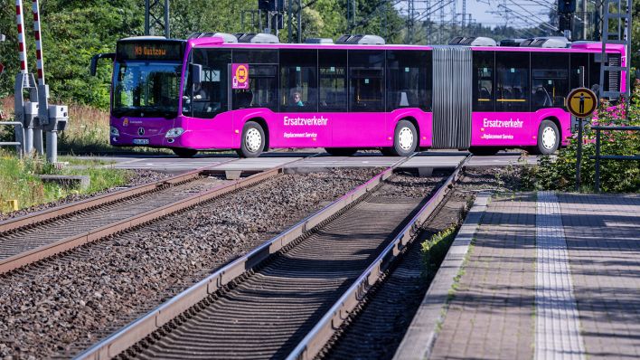 Ein Ersatzbus der Deutschen Bahn fährt über einen Bahnübergang auf der wegen Bauarbeiten gesperrten zweigleisigen Schienenstrecke. Busse ersetzen in den nächsten neuen Monaten die Personenzüge auf der Strecke zwischen Berlin und Hamburg fotografiert am 06.08.2025.(Quelle: picture alliance/dpa/Jens Büttner)