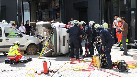 Feuerwehrleute stehen vor einem auf der Seite liegendem Auto: In der Ausbildung bei der Berufsfeuerwehr Mainz wird auch immer wieder der Ernstfall geprobt, zum Beispiel ein Verkehrsunfall.