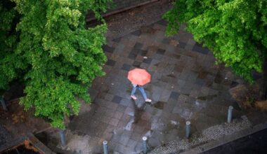 Symbolbild:Eine Person mit Regenschirm geht bei leichtem Regen auf einem nassem Gehweg im Bezirk Charlottenburg-Wilmersdorf entlang.(Quelle:picture alliance/SZ Photo/O.Schülke)