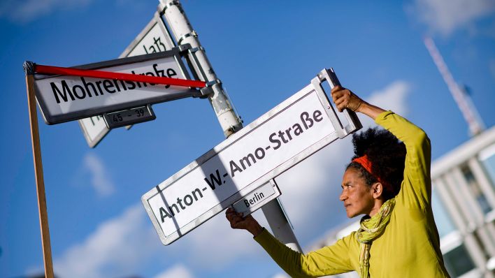 Deutschland, Germany, Berlin, 23.08.2017 Protestler mit Strassenschild Anton-W.-Amo-Strasse als neuen Namensgeber in Erinnerung an den ersten deutschen schwarzen Akademiker Anton Wolhelm Amo am Schild Mohrenstrasse am Umbenennungsfest Mohrenstraße anlaesslich des Internationalen Tags zur Erinnerung an den Versklavungshandel in Berlin