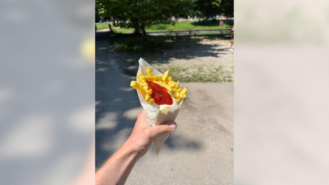 Eine Hand hält eine Portion Pommes. 