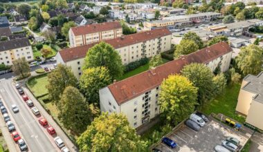 Eine Luftaufnahme eines Wohngebiets mit mehreren Wohnblöcken, umgeben von Bäumen und Straßen.