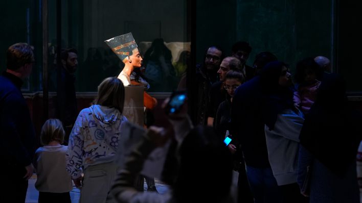 Symbolbild: Besucher am 01.12.2024 bei der Büste der Nofretete aus Kalkstein und Gips im aegyptischen Museum im Nordkuppelsaal des Neuen Museums auf der Museumsinsel. Nofretete war die Hauptgemahlin (Grosse koenigliche Gemahlin) des Koenigs (Pharaos) Echnaton. (Quelle: Picture Alliance/Marc Vorwerk)