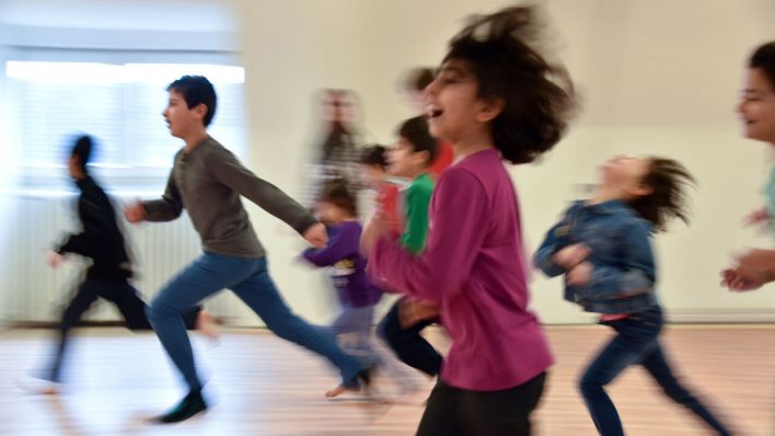 Symbolbild: Flüchtlingskinder rennen in der Erstaufnahmeeinrichtung im Rahmen der Kinderbetreuung durch einen Sportraum. (Quelle: dpa/Zucchi)