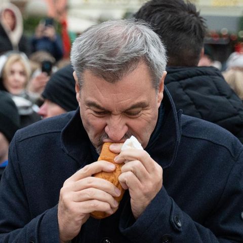 Markus Söder isst eine Wurst im Brötchen