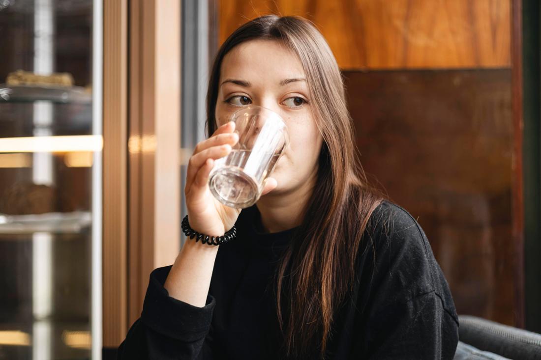 Eine junge Frau trinkt ein Glas Wasser.