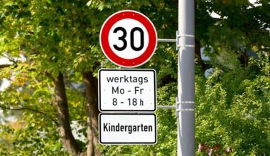 Ein Verkehrsschild in einer grünen Umgebung, das eine Geschwindigkeitsbegrenzung von 30 km/h anzeigt, gültig an Werktagen in der Nähe eines Kindergartens. (Quelle: dpa/Michael Bihlmayer)