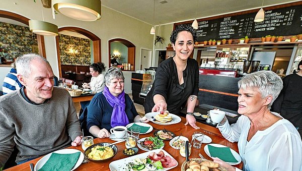 Pancakes mit frischen Beeren, Joghurt mit Obstsalat im Weckglas, Lachs, Oliven, Hummus, Antipasti-Gemüse, Tomate-Mozzarella – und es hört nicht auf. Nach und nach serviert Chefin Tülay Güreli (2. v. r.) Gästen, wie den Geschwistern Althoff am Tisch, immer weitere Köstlichkeiten. - © Barbara Franke