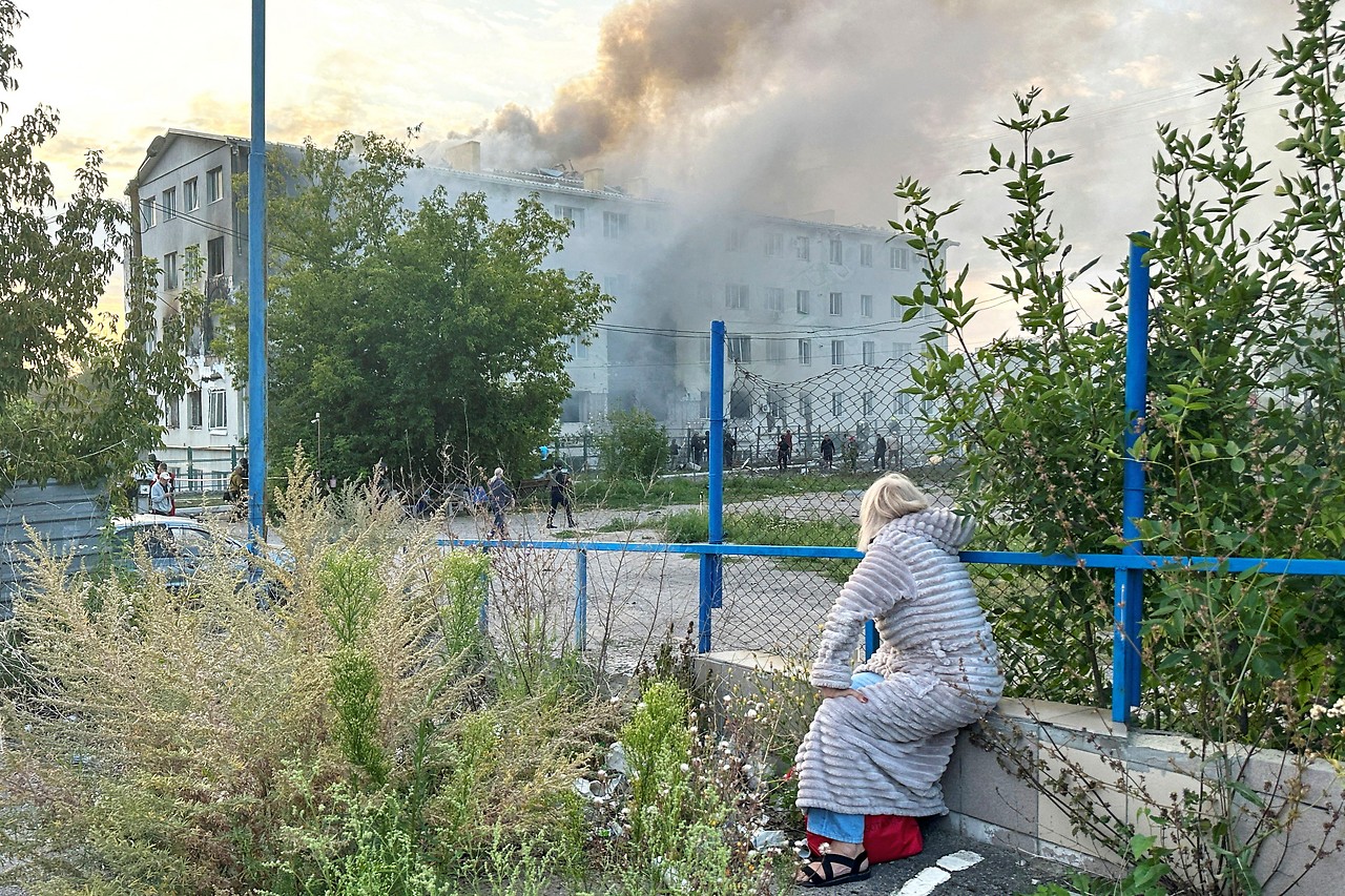 Frau vor brennendem Wohnhaus nach Drohnenangriff in der Ukraine