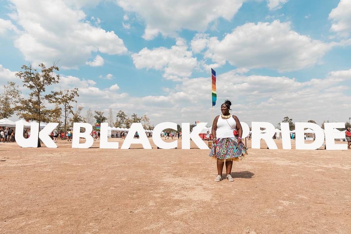 Attendee posing for a picture in front of the UK Black Pride sign