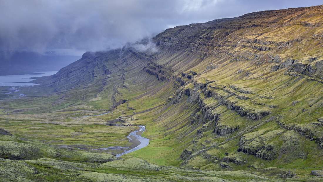Es ist ein Fjord und eine Landschaft in Island zu sehen. 