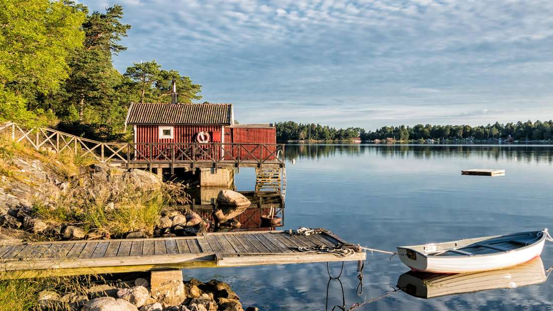 Schären in Schweden mit einem roten Holzhaus und Ruderboot