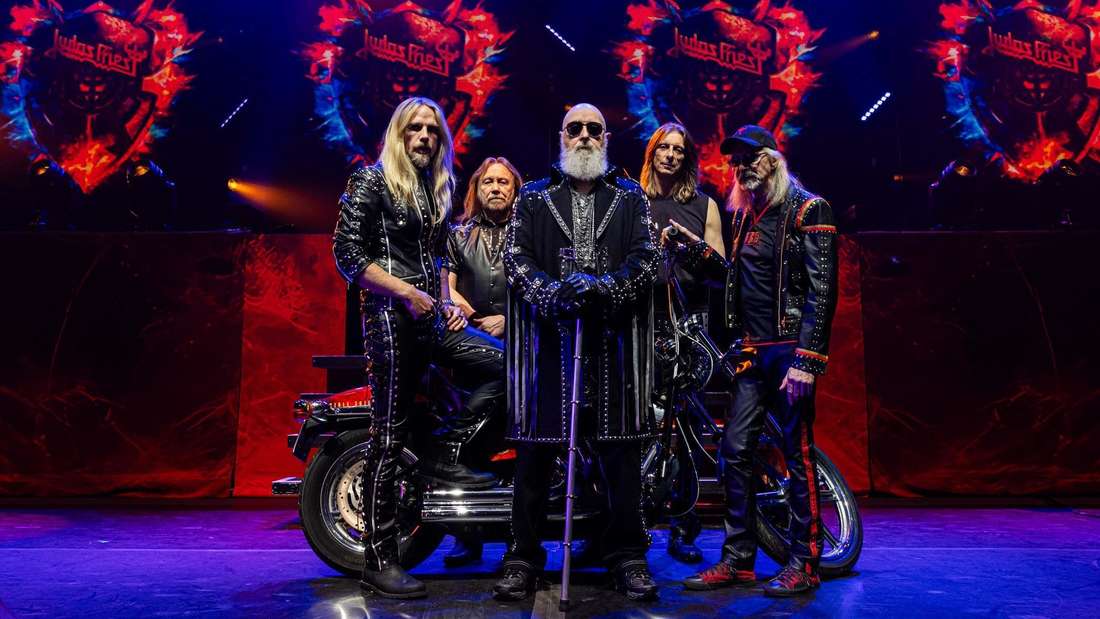 Judas Priest posieren vor einem Motorrad.