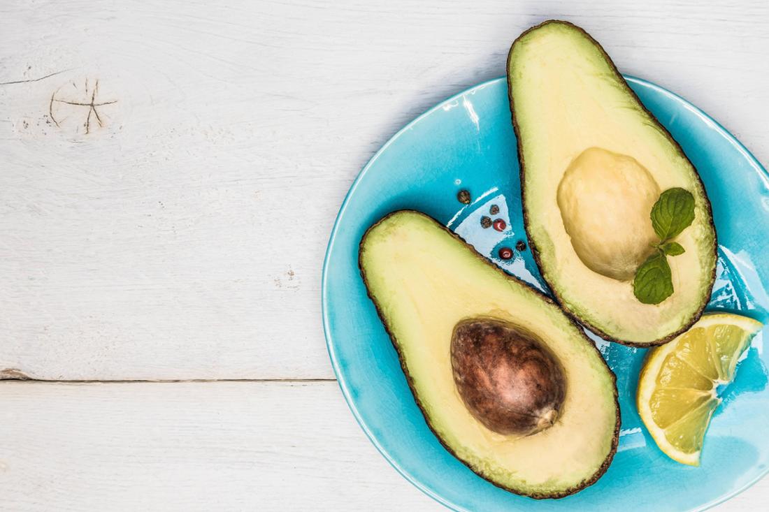 Eine aufgeschnittene Avocado liegt auf einem blauen Teller.