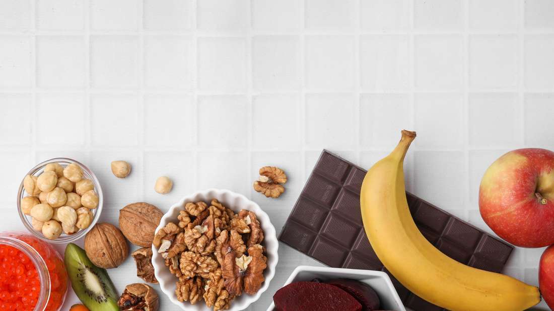 Many different products on white tiled table, flat lay with space for text. Natural sources of serotonin
