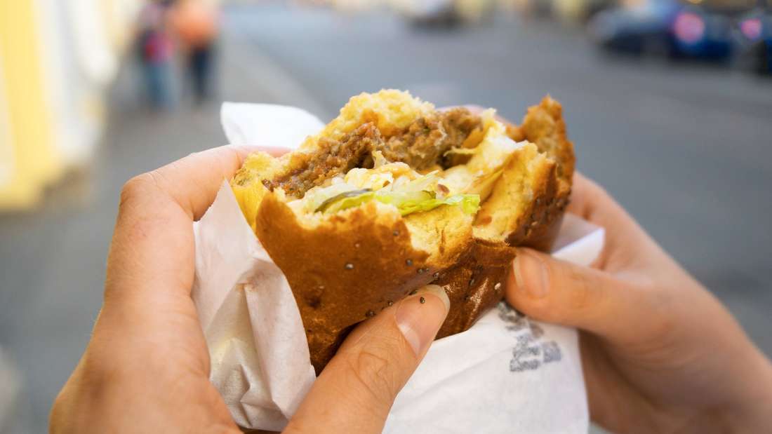 Frau isst einen Hamburger auf der Straße.