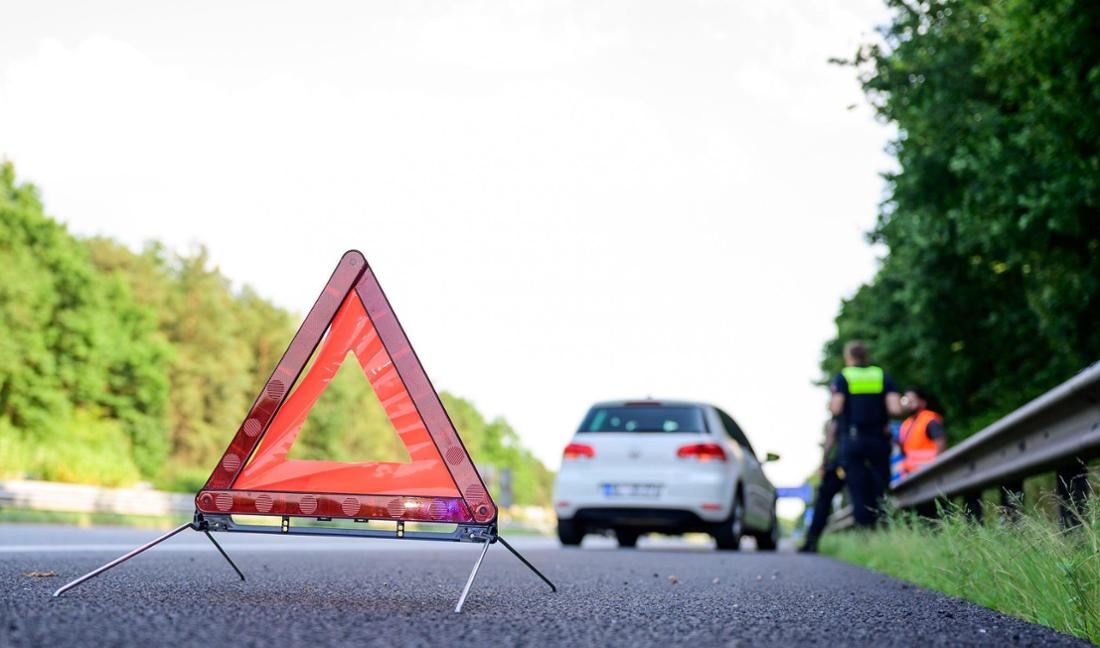 Mit Warndreieck steht nach einer Panne auf der Autobahn