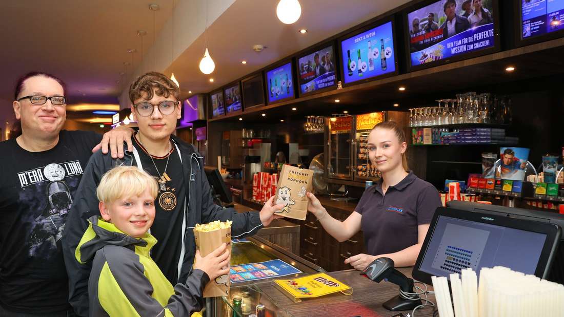 Ralf Hedtkamm (links) mit seinen Söhnen Ansgar und Torben beim Popcorn holen von Kino-Servicekraft Merle Günther. 