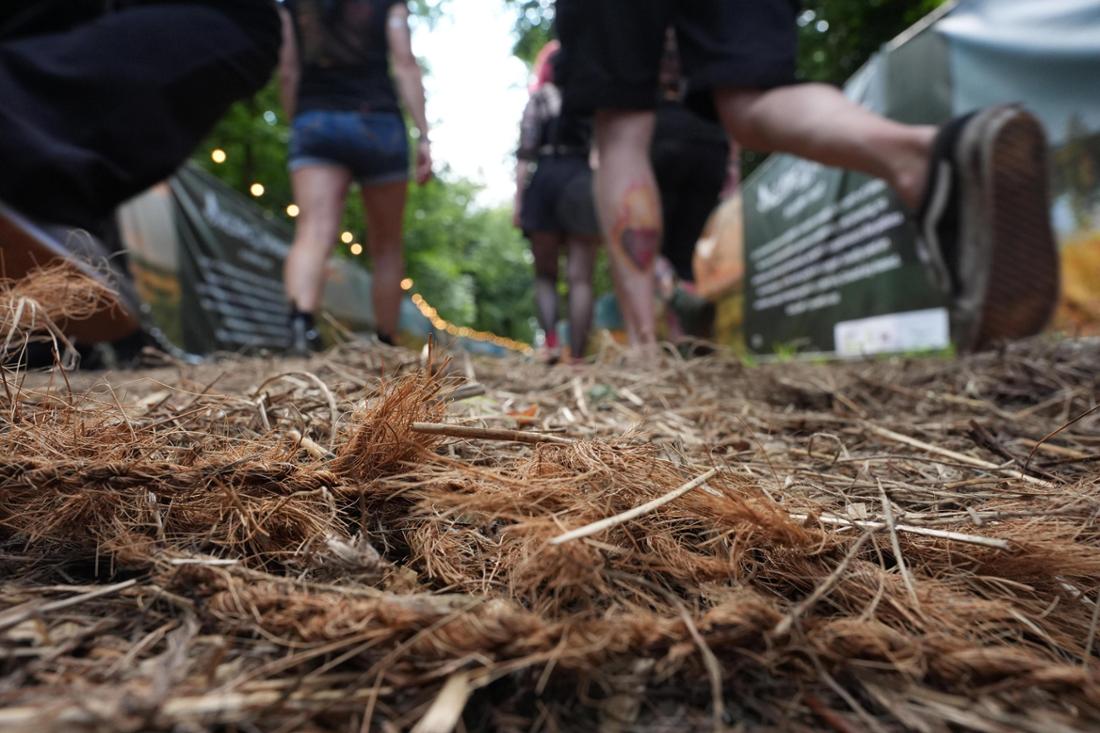 Menschen laufen über Moorgras-Matten gegen Matsch.