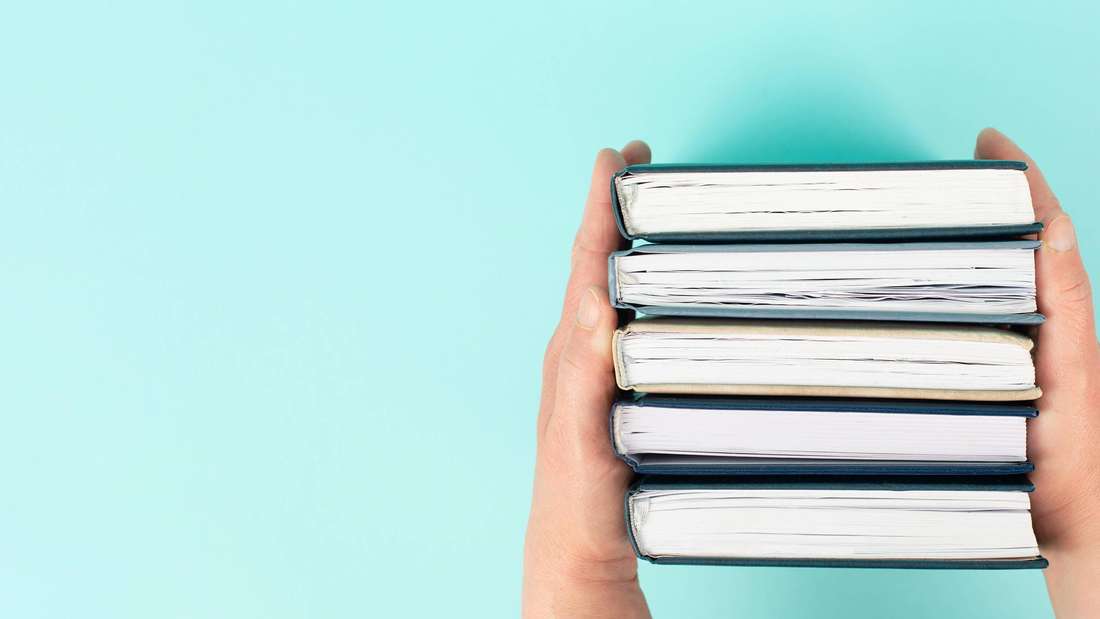 Hände halten Stapel von Büchern (Symbolbild)