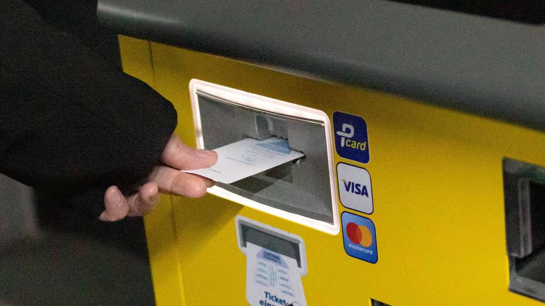 Frau steckt ein Parkticket in den Kassenautomaten
