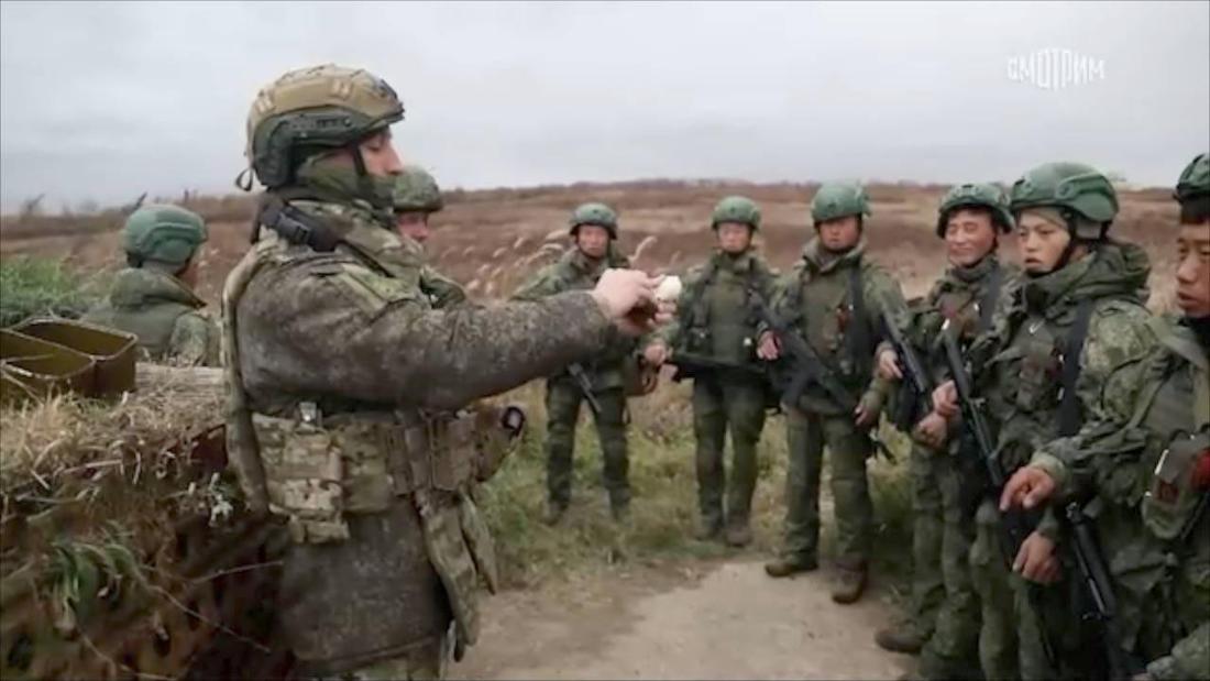 russischer Soldat, der eine Gruppe nordkoreanischer Kameraden einweist