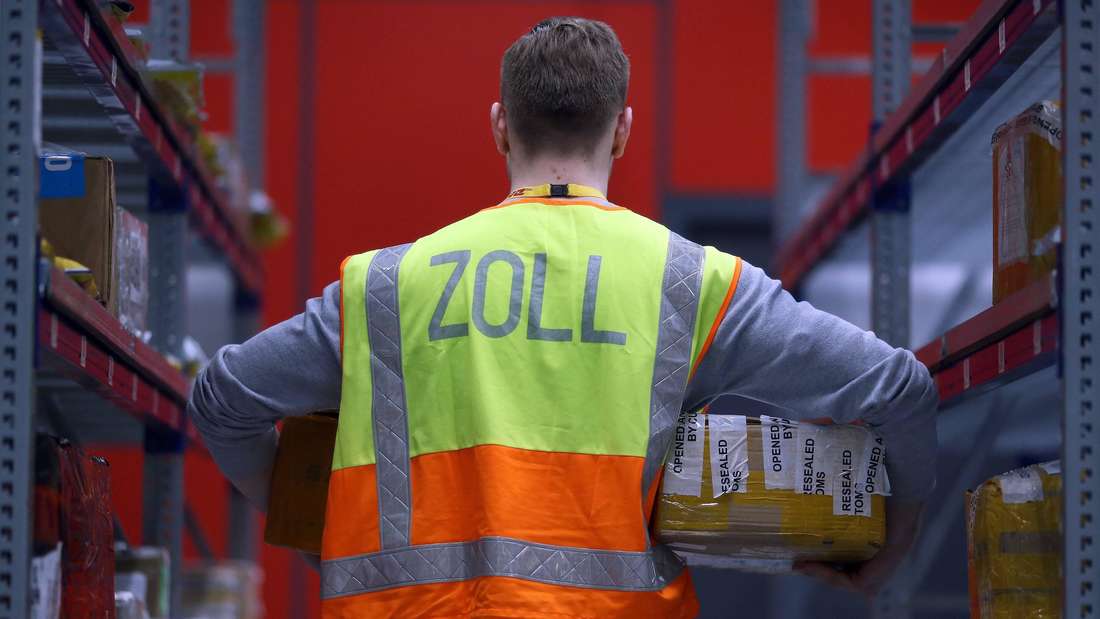 Zoll-Mitarbeiter mit Paket in der Hand in der Rückansicht.