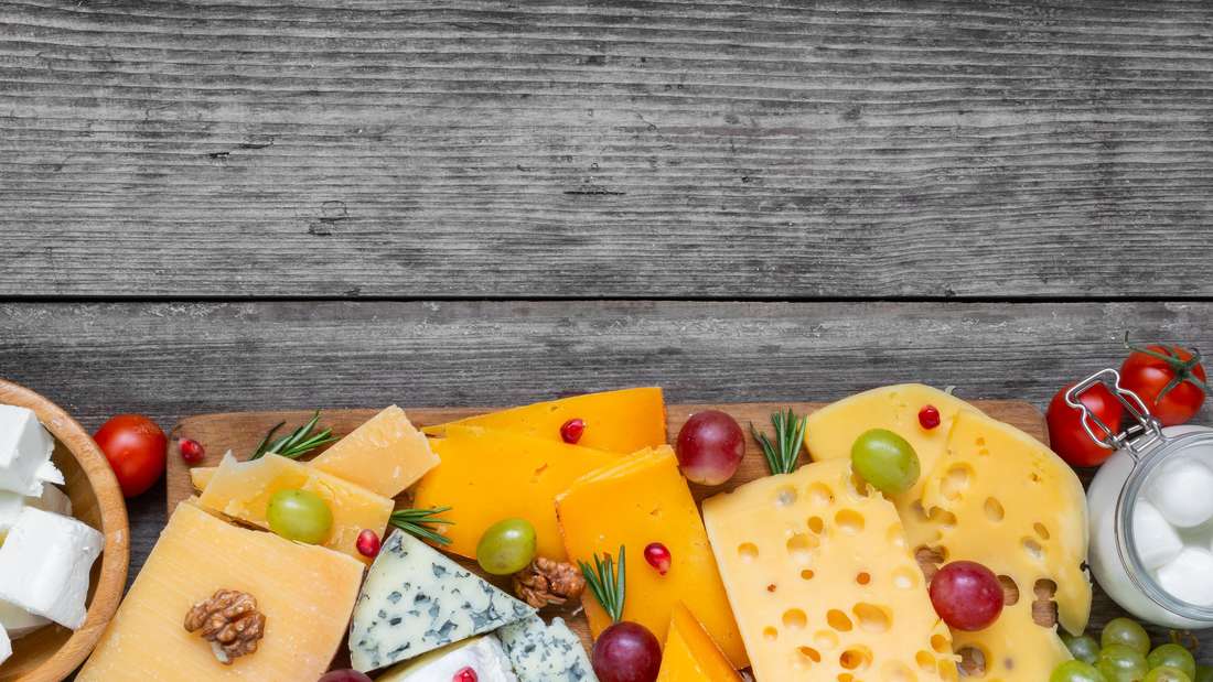 Assortment cheeses on wooden cutting board. Cheese plate served with grape fruits, tomatoes Käsesorten 