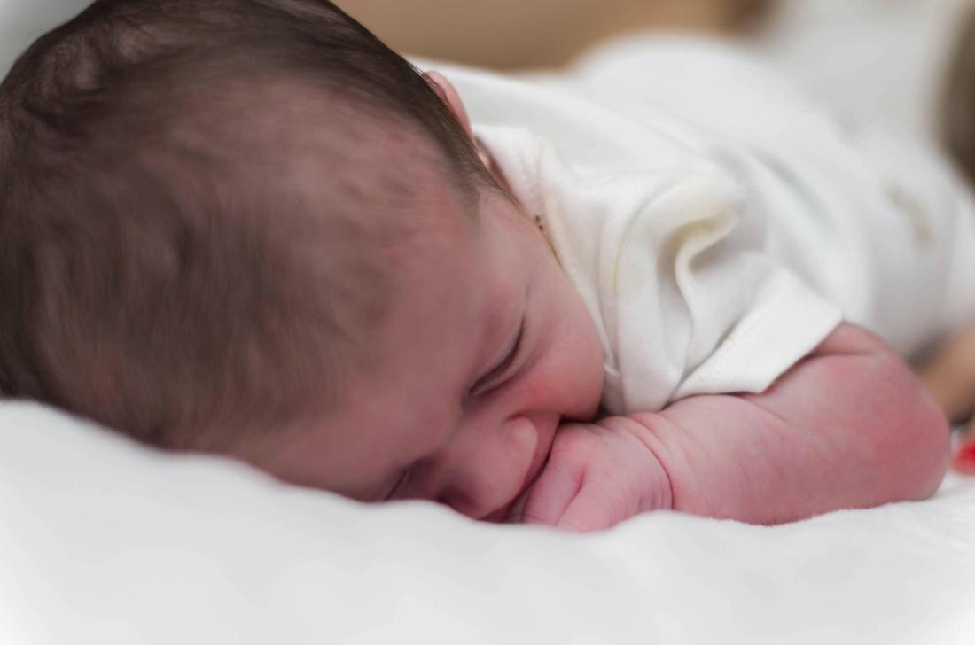 7 Tage altes Neugeborenes, Nahaufnahme des Gesichts eines im Bett liegenden Babys