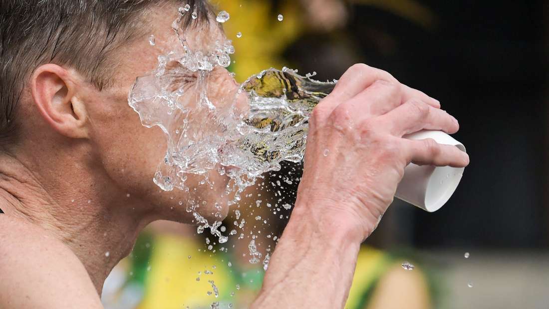 Ein Mann schüttet sich Wasser ins Gesicht