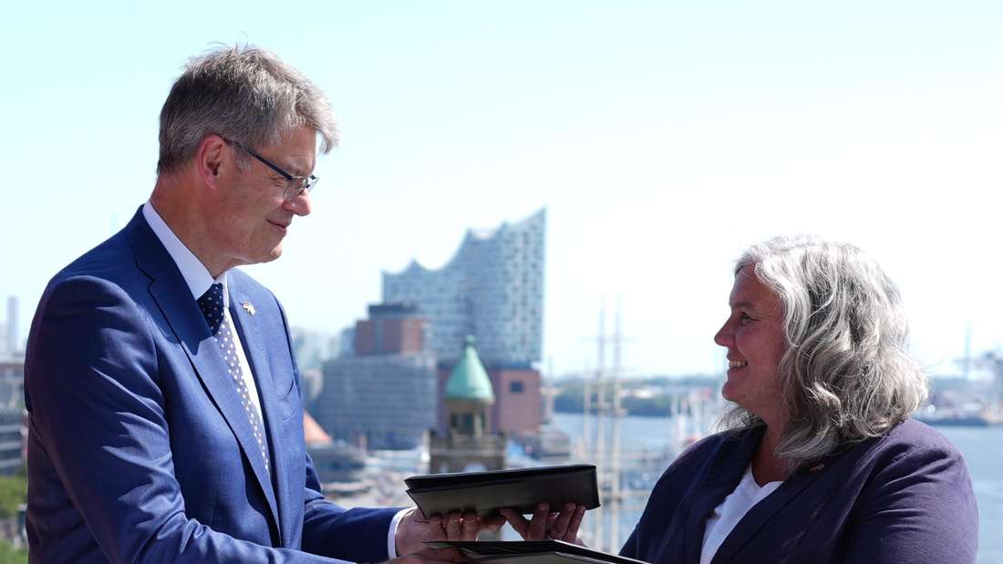 13.08.2025, Hamburg: Patrick Schnieder (l, CDU), Bundesminister für Verkehr, und Heidi Alexander (r), Verkehrsministerin von Großbritannien, tauschen auf der Dachterrasse des Bundesamts für Seeschifffahrt und Hydrographie die gemeinsame Absichtserklärung für eine künftige Direktverbindung im grenzüberschreitenden Schienenpersonenfernverkehr zwischen Deutschland und dem Vereinigten Königreich nach der Unterzeichnung aus. Foto: Marcus Brandt/dpa +++ dpa-Bildfunk +++