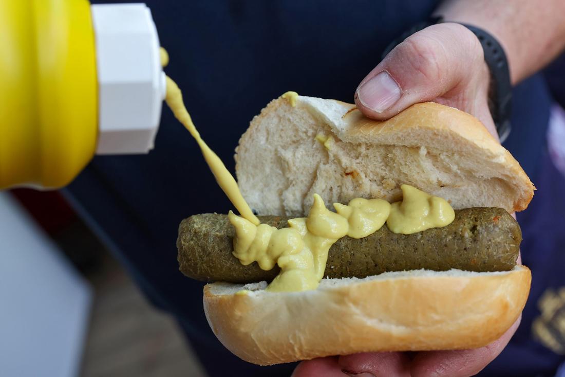 Eine vegane Bratwurst wird mit Senf gewürzt. (Symbolbild)