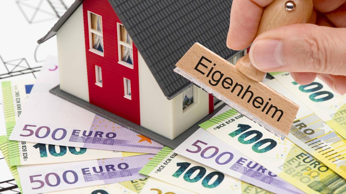Hausmodell steht auf Geldscheinen, Hand hält Stempel