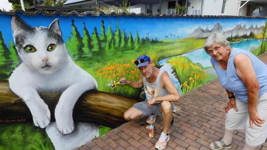 Ein Mann, der Graffiti sprayt, und eine ältere Frau vor einer bunt bemalten Wand