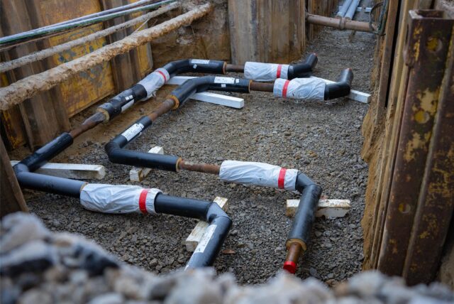 Fernwärme-Rohre liegen offen im Boden in einer Baustelle der Hertener Stadtwerke.