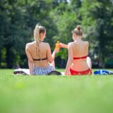 Zwei junge Frauen sonnen sich auf einer Wiese.