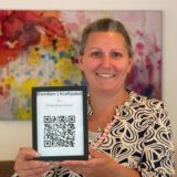Sarah Schröder hält einen QR-Code in die Kamera.