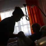 Eine Frau wird in ihrem Bett von einer Pflegerin betreut